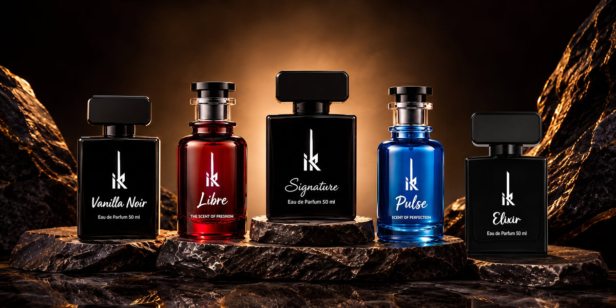 Four perfume bottles from the brand IK are lined up on dark rocks against a dramatic golden background. From left to right, the bottles are Vanilla Noir (black), Libre (red), Signature (black), Pulse (blue), and Elvir (black).